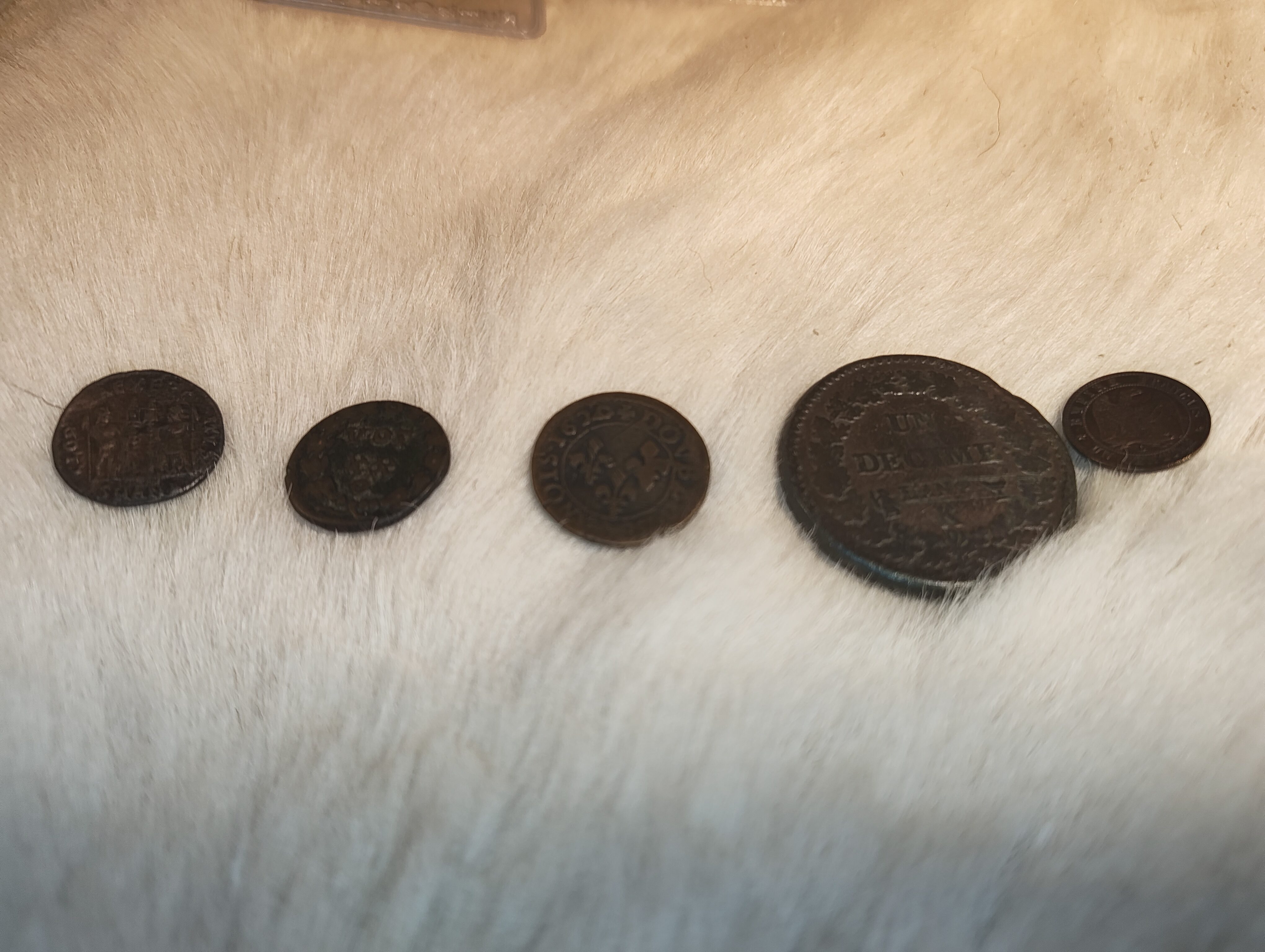 Trois monnaies : une romaine de 162 apr. J.-C., une de la Révolution française, une du Second Empire