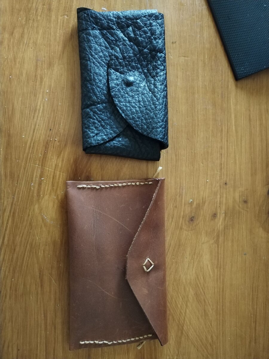 Deux pochettes en cuir : une noire à pression en cuir grainé, une marron style enveloppe avec rivet diamant